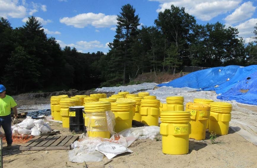 drums and tarps covering soil piles 