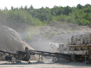 Dust fills the air around a rock crushing operation.