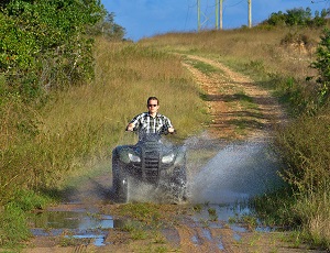 ATV being driven through muddy water on a dirt road