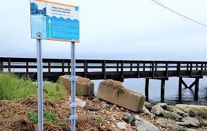 a sign and a bridge over coastal water