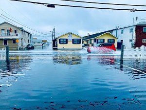 a flooded street with a home in the background
