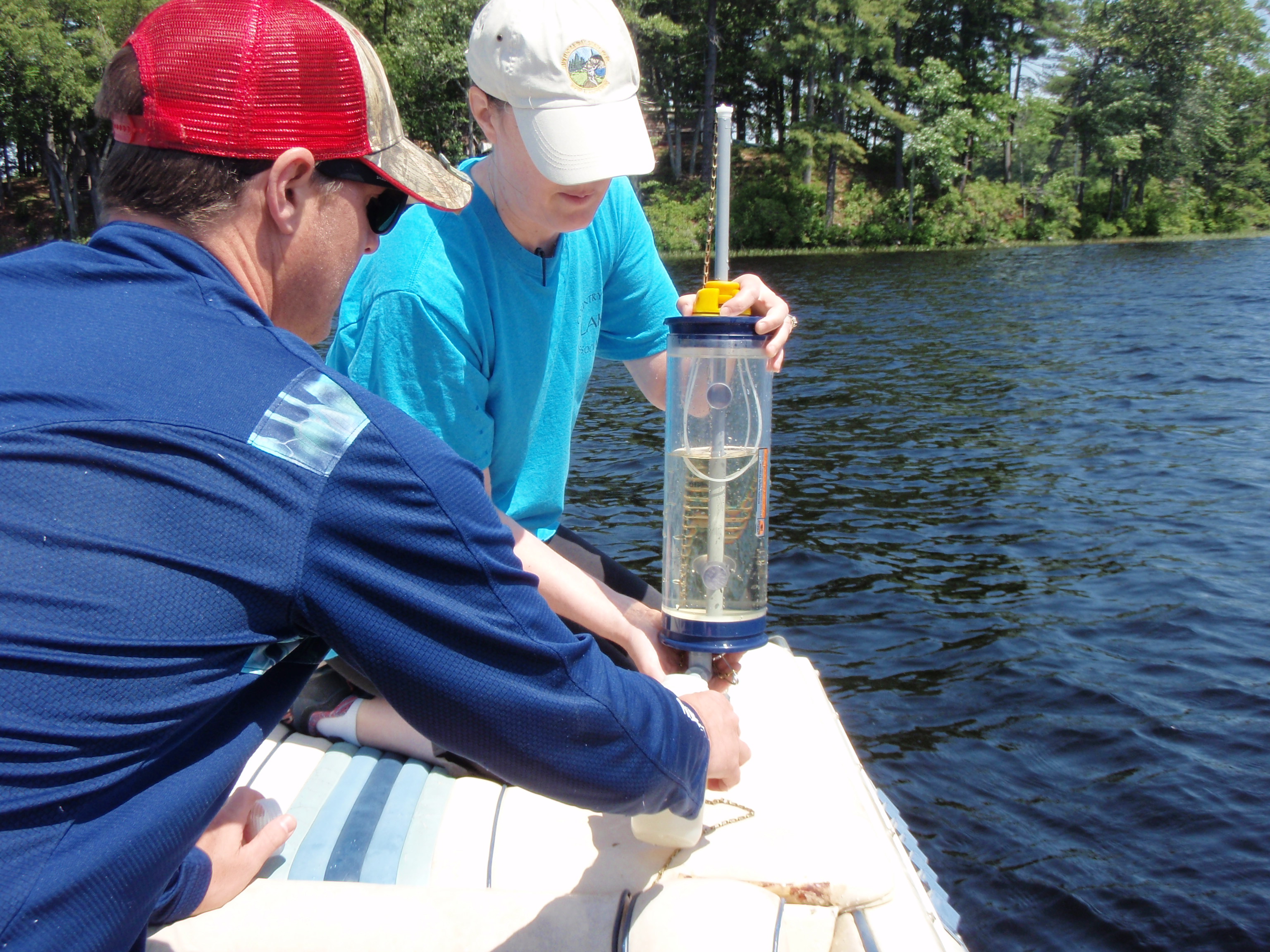 Two volunteers collect water samples from a lake.