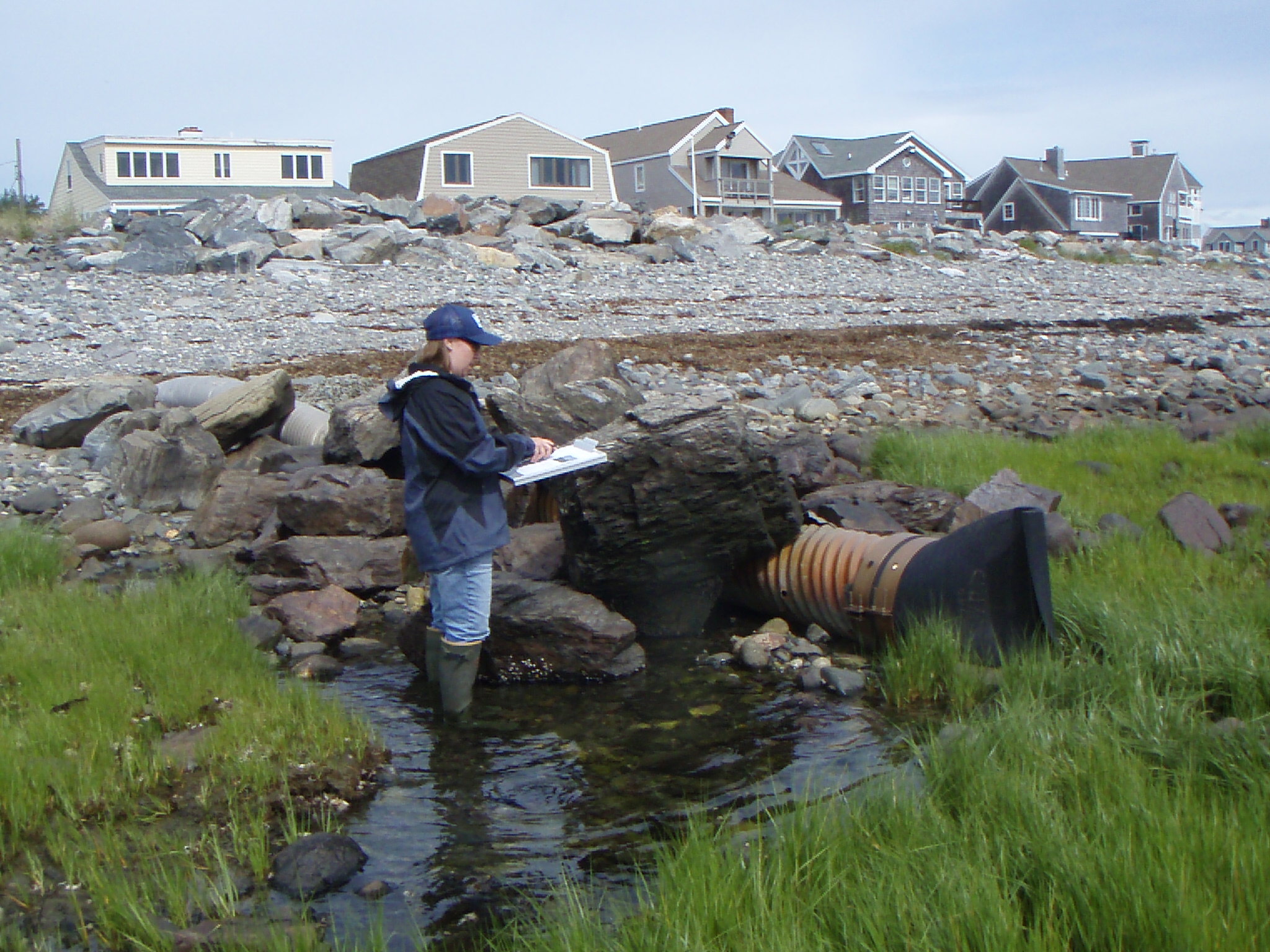 photo of worker noting pollution source as stormwater outfall