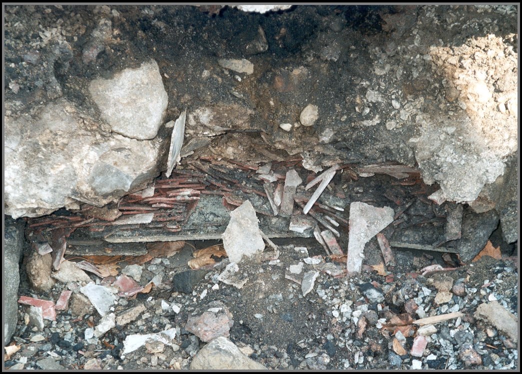 trench with exposed asbestos waste on bank