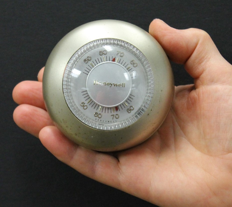 a picture of a hand holding a thermostat