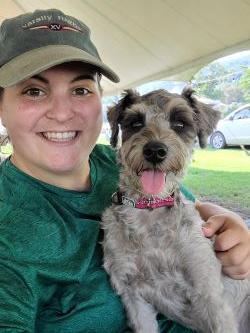 Woman wearing green holding a grey dog.