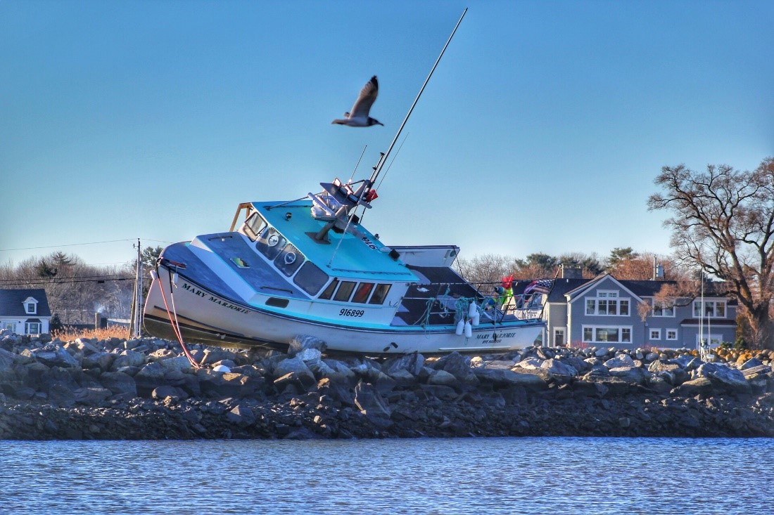 A fishing boat sitting on rocks along the shoreline.