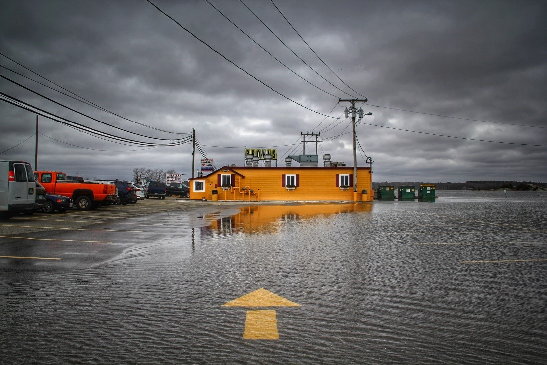 A flooded parking lot with an arrow on the pavement pointing to a flooded restaurant.