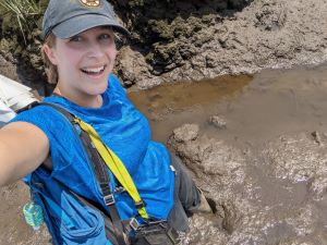 a woman poses for a selfie while standing in mud