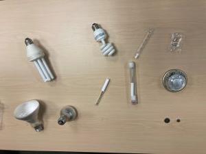 devices containing mercury including different light bulbs, button batteries, a silver thermometer and a thermostat