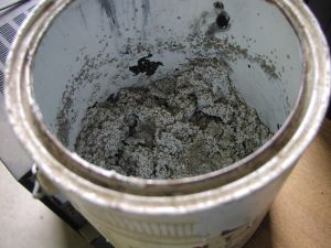 dried, gray latex paint in a metal can