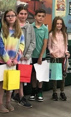 Four students holding colorful bags with prizes.