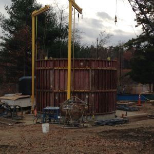 two yellow cranes over round concrete lining of well and metal form for the next concrete section