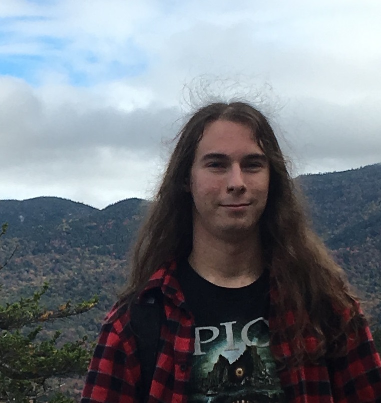 Man in red and black plaid with mountains in the background
