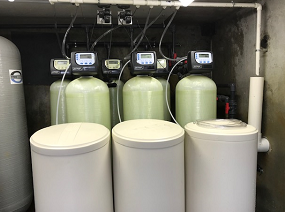 Three white cylindrical containers in front of six green cylindrical containers with plastic meters on top of each