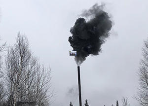 dark smoke is emitted from a smoke stack