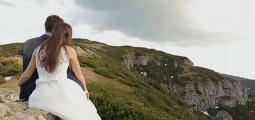 a bride and groom look out at a mountain view