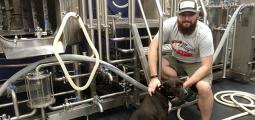 a man stands inside his brewery with his dog