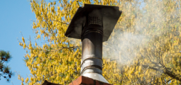 wood smoke emits from a metal chimney