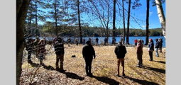 a group of people stand in a circle surrounded by trees
