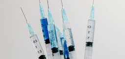  a hand with a blue medical glove on holding needle syringes