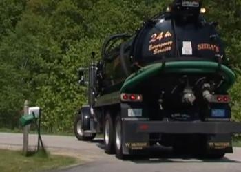 a septic hauling truck backs up to a driveway